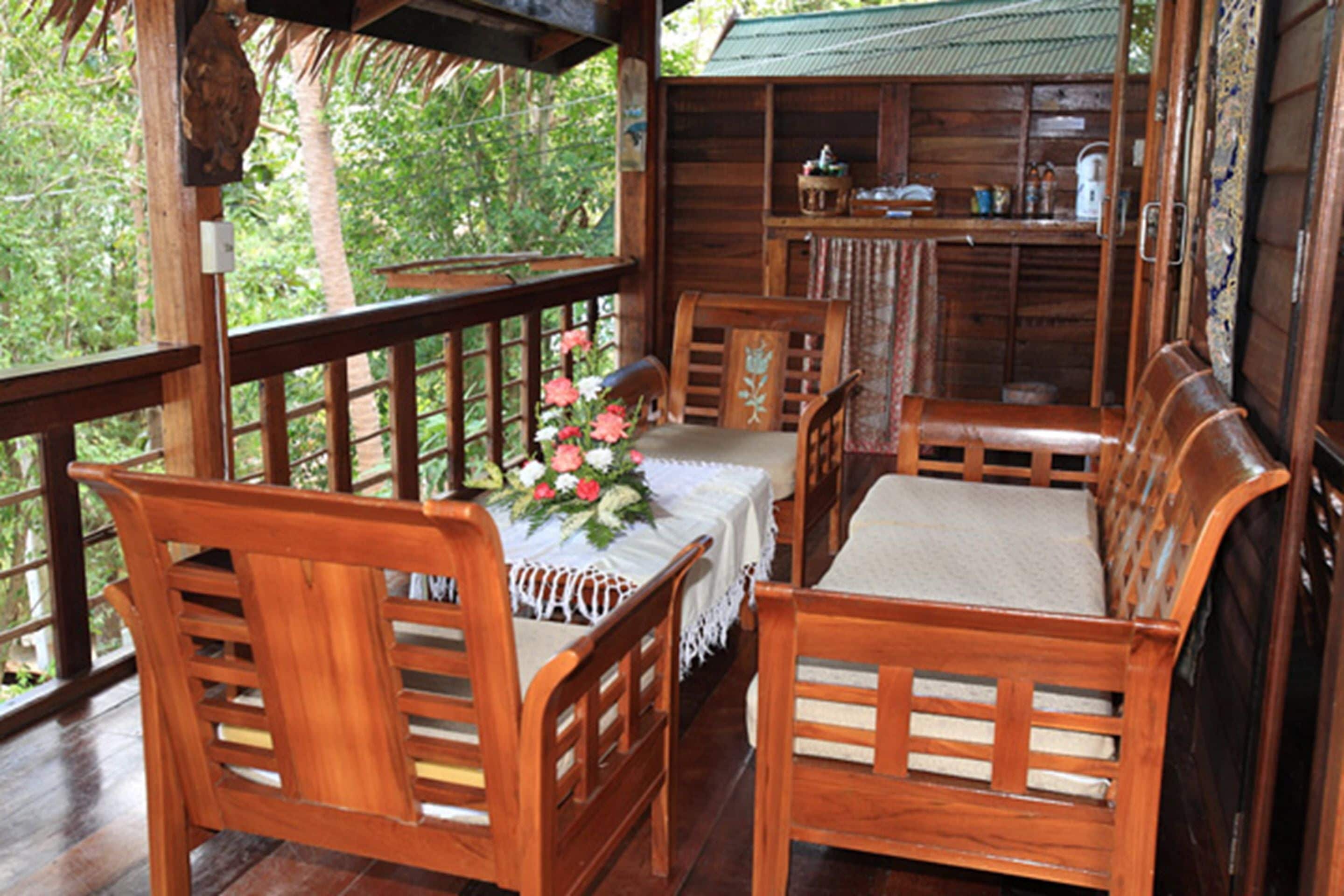 A wooden cabin with a dining area featuring a table with a floral centerpiece, wooden chairs, and a bench.