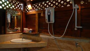 A bathroom with a wooden interior, a sink, a mirror, and a shower with a hose.