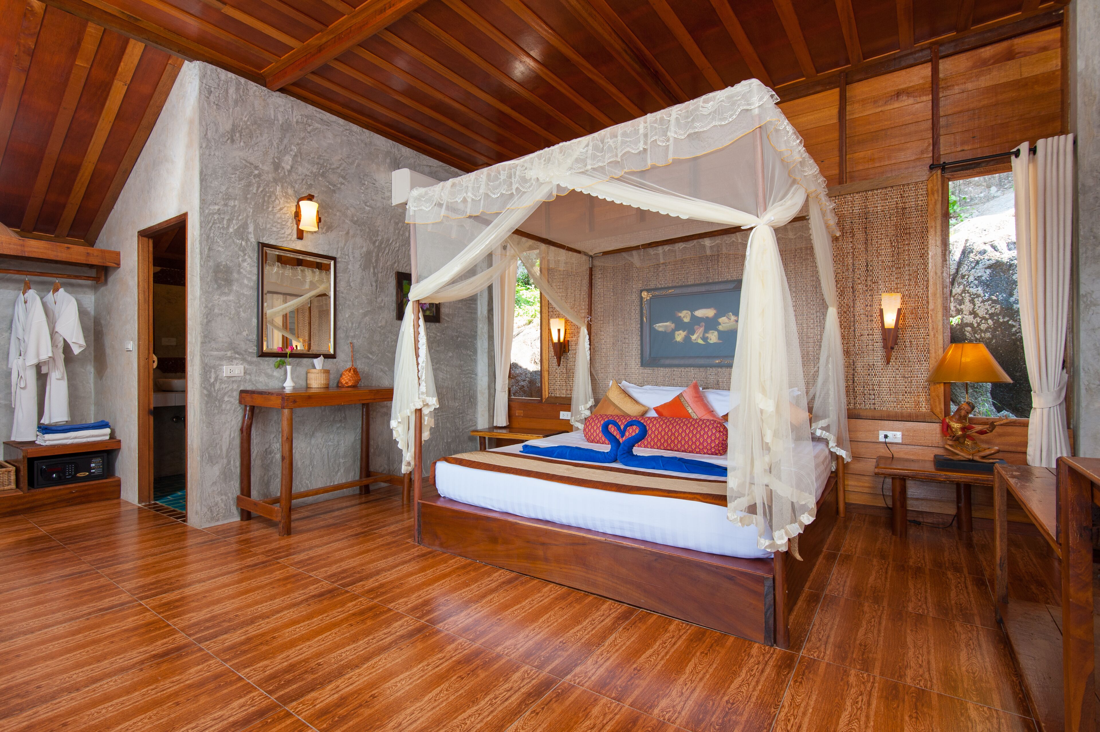 Slaapkamer met een houten plafond, een hemelbed, een nachtkastje, een lamp en uitzicht op de omgeving.