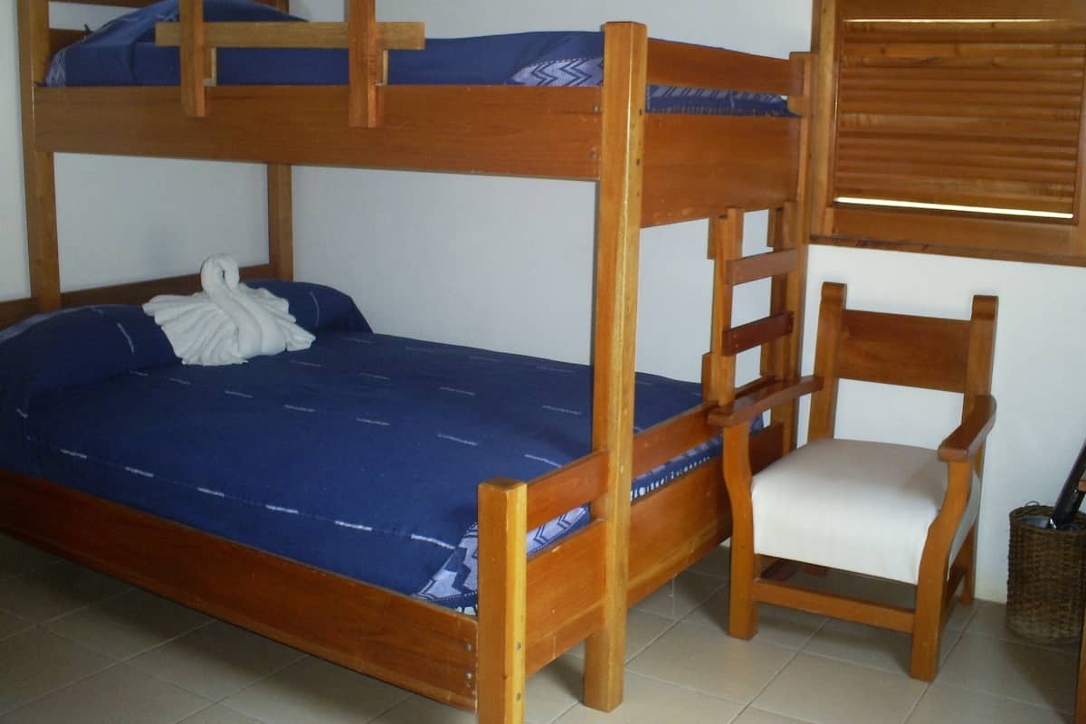 A bunk bed with a blue mattress and a wooden chair beside it.
