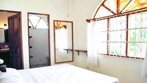 A room with a bed, a mirror, and a window with bars.