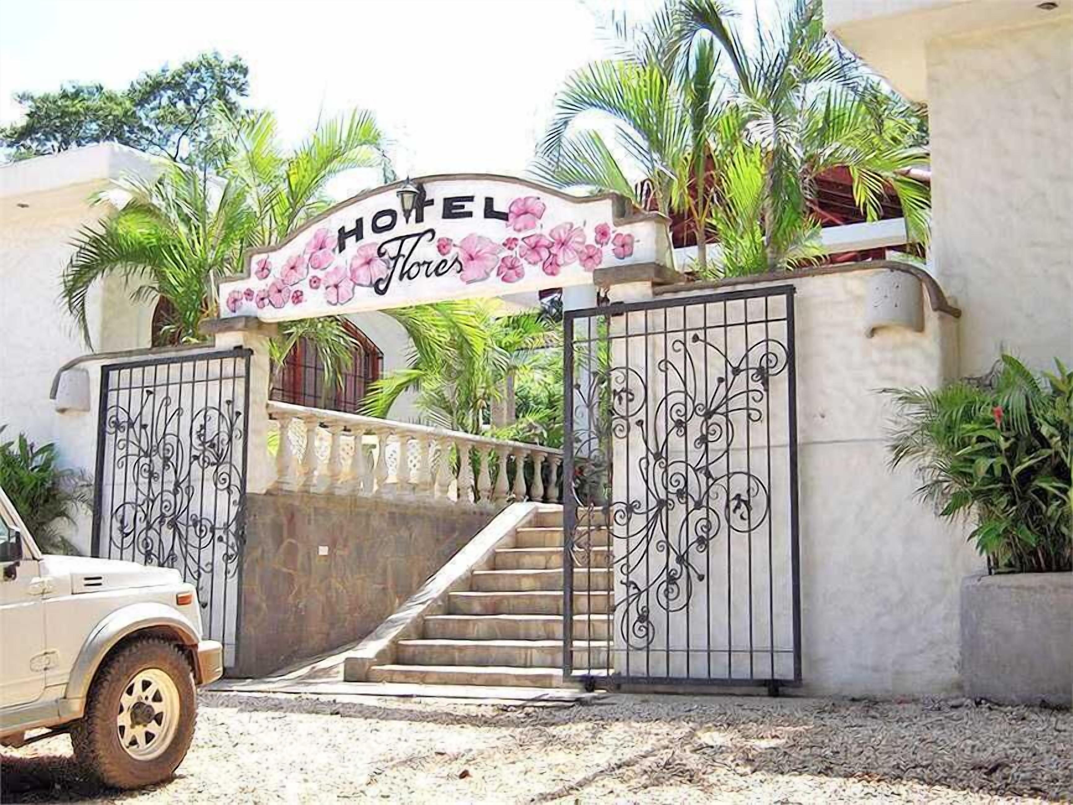 Entrada de hotel con un letrero que dice "HOTEL Flores" y una escalera que conduce a la entrada.