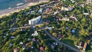 An aerial view of a coastal town with a beach, residential areas, and a prominent modern building.