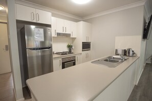 Executive appartement | Privékeuken | Een koelkast, een microgolfoven, een kookplaat, een vaatwasser