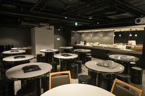 A restaurant interior with round tables, stools, and a bar area. - Hotel Mystays Nagoya Nishiki (Nagoya)