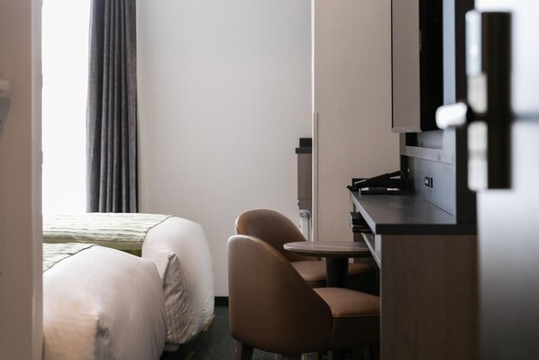 A hotel room with a bed, two chairs, a small table, and a television. - Hotel Mystays Nagoya Nishiki (Nagoya)
