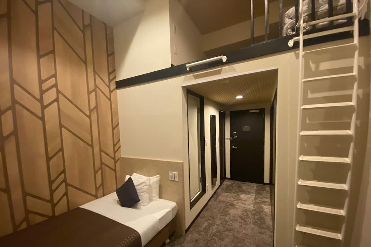 A hotel room with a bed, a small desk, a wardrobe, and a walk-in closet.