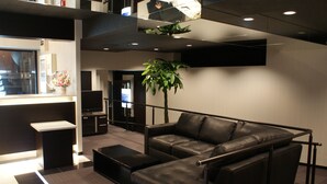 A modern lobby with a leather sofa, a small table, and a potted plant. - HOTEL LiVEMAX Esaka (Suita)