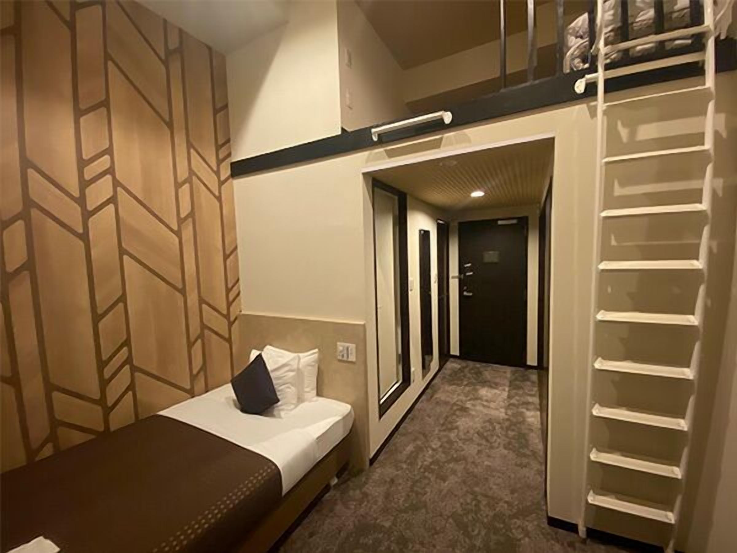 A hotel room with a bed, a desk, a wardrobe, and a bunk bed.