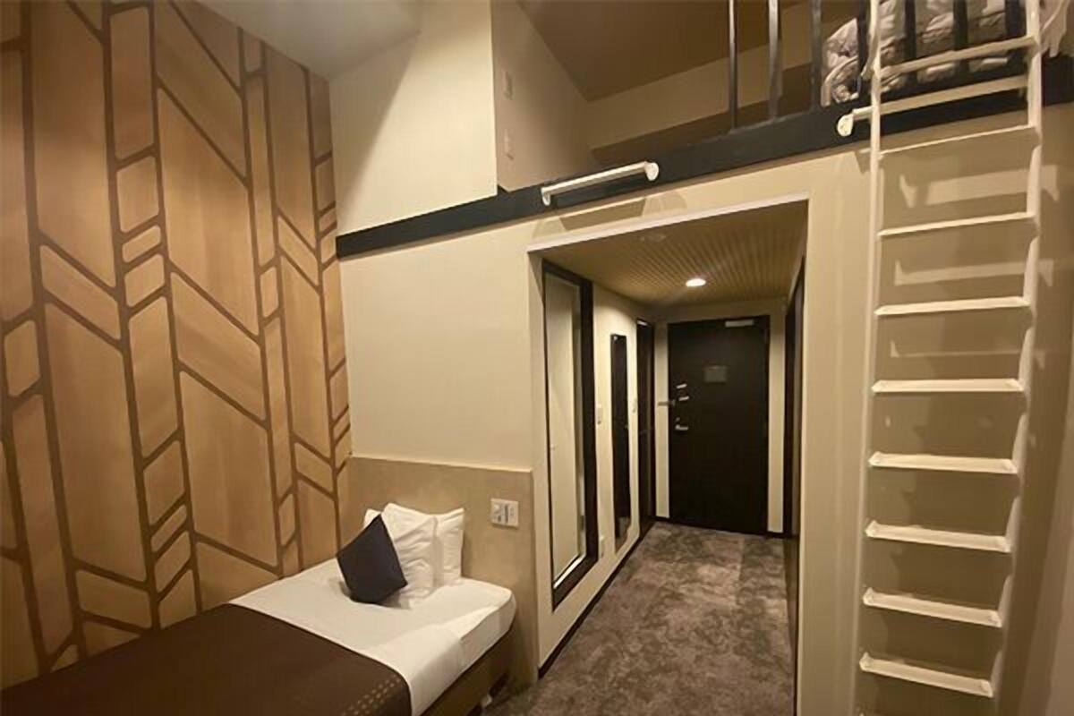 A hotel room with a bed, a desk, a wardrobe, and a bunk bed.