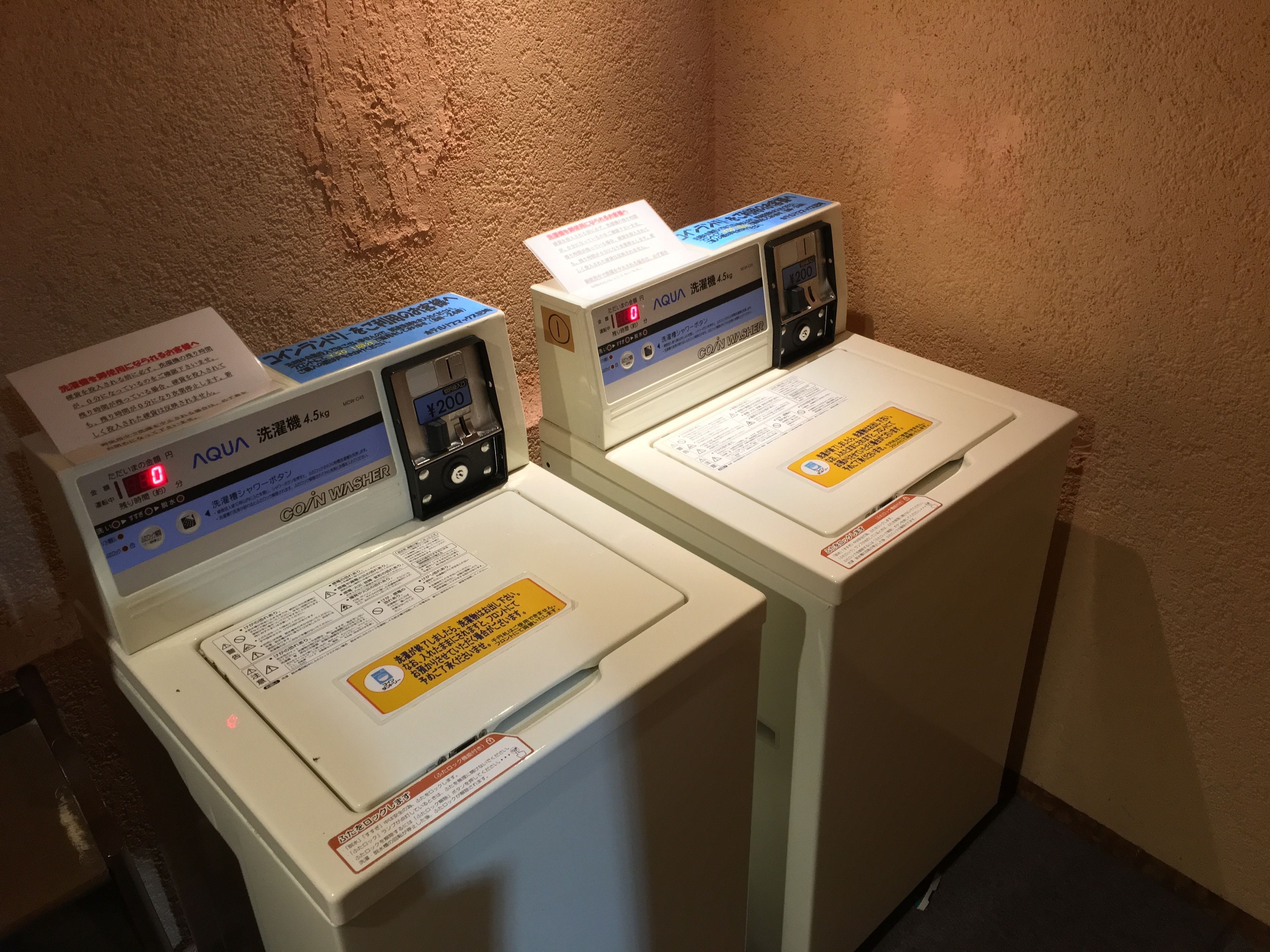 Two white washing machines with digital displays and instructions in Japanese.