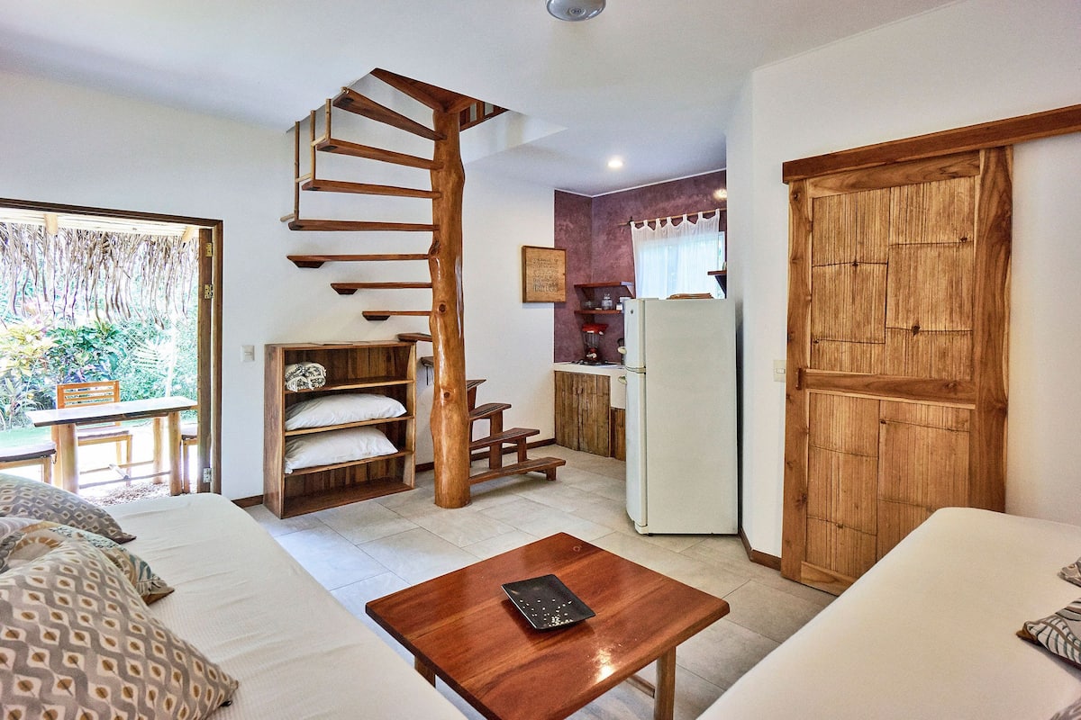A compact living space with a spiral staircase, a kitchenette, and a dining area.