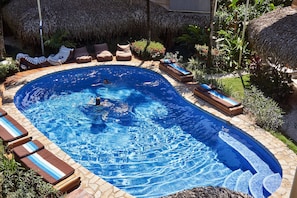 A swimming pool with lounge chairs and a thatched roof structure. - Otro Lado Lodge and Restaurant (Cobano)