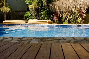 A pool with wooden deck and tropical plants. - Otro Lado Lodge and Restaurant (Cobano)
