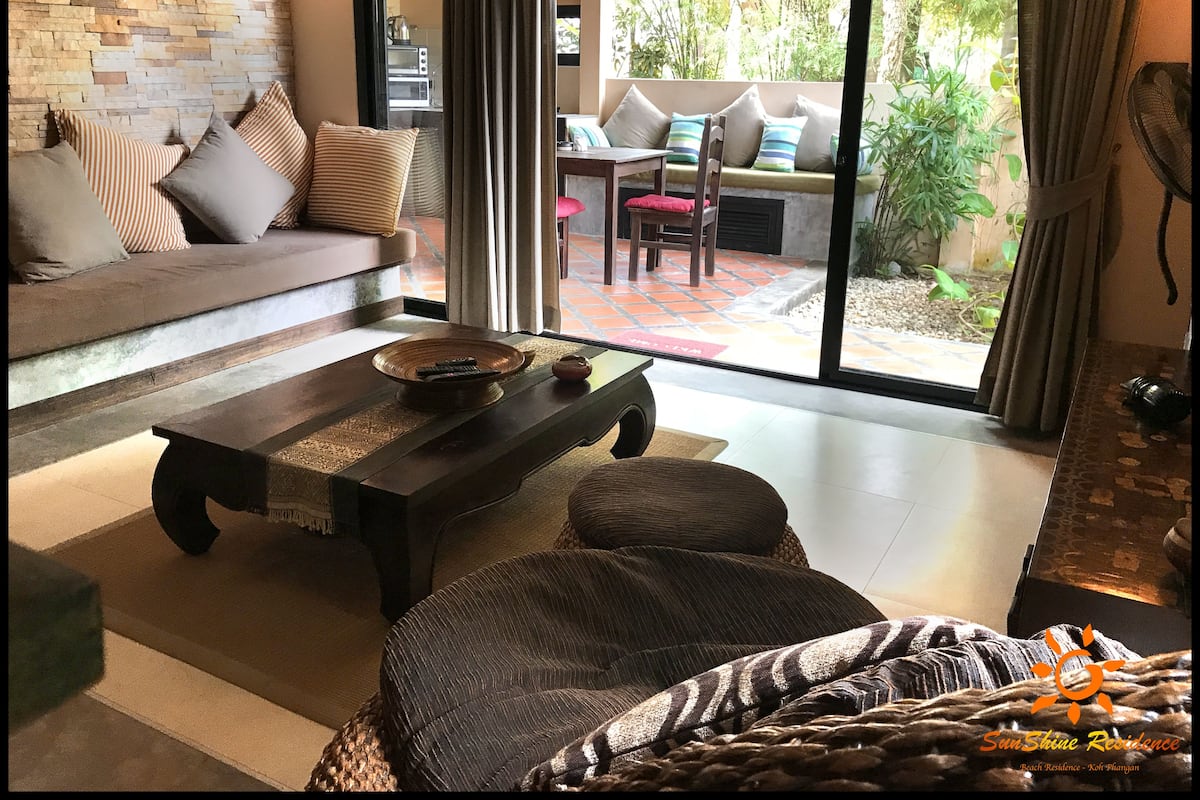 A modern living room with a sofa, a coffee table, and a view of the outdoors.