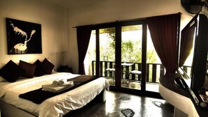 A bedroom with a bed, a fan, a window with curtains, and a balcony with outdoor furniture. - Cocooning Hotel (Koh Samui)