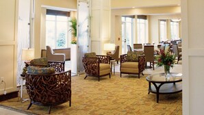 A spacious lobby with high ceilings, large windows, and modern furniture. - Hilton Garden Inn Watertown/Thousand Islands (Watertown)