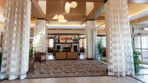 A spacious lobby with a patterned carpet, wooden beams, and a reception desk. - Hilton Garden Inn Watertown/Thousand Islands (Watertown)