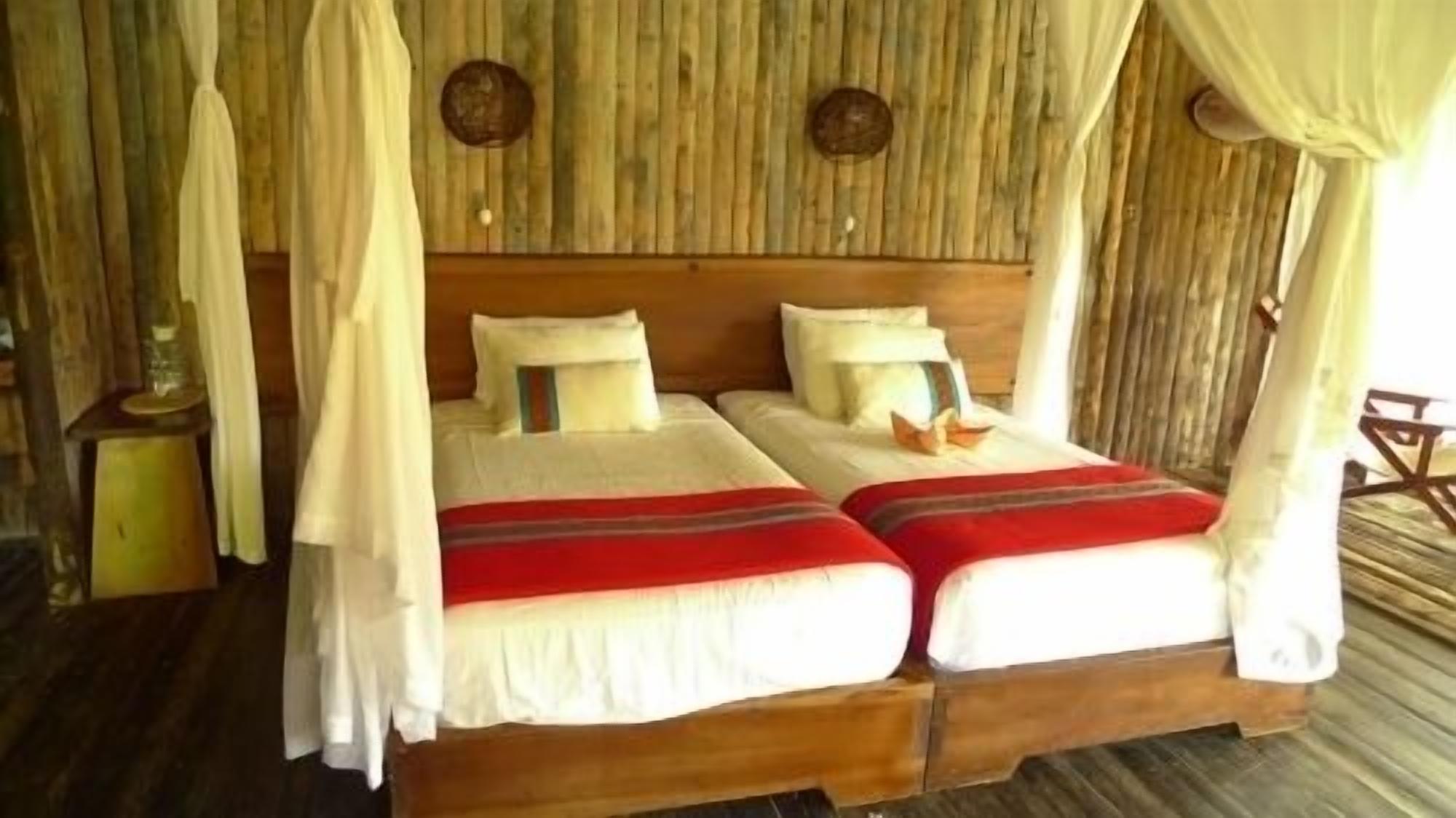 Un lit double à baldaquin, deux oreillers et une couverture rayée rouge et blanche.