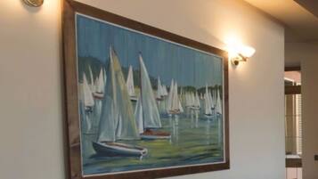 Una pintura de veleros en el agua, enmarcada y colgada en una pared.