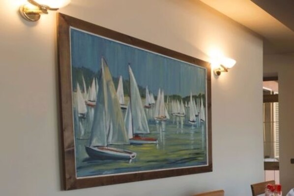 Una pintura de veleros en el agua, enmarcada y colgada en una pared.