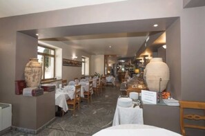 A restaurant with tables set for dining, a large vase centerpiece, and a view of the dining area. - Sirio Hotel (Dormelletto)