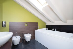 A modern bathroom with a freestanding bathtub, a bidet, and a large sink. - Sirio Hotel (Dormelletto)