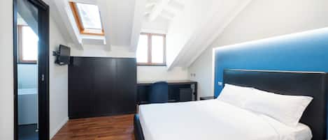 Ein Schlafzimmer mit Bett, Schreibtisch und Stuhl. Über dem Bett ein Oberlicht und neben dem Schreibtisch ein Fenster.