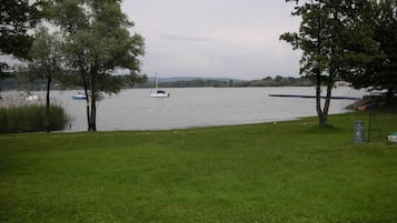 Un espacio con césped, un lago, un velero y árboles.