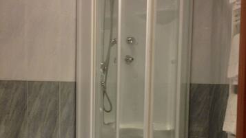 A corner bathroom with a glass-enclosed shower, a pedestal sink, and a toilet.