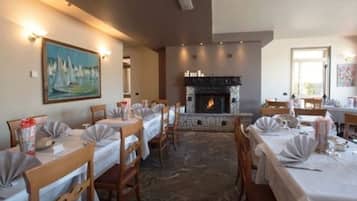 A dining area with tables set for a meal, a fireplace, and a painting on the wall.