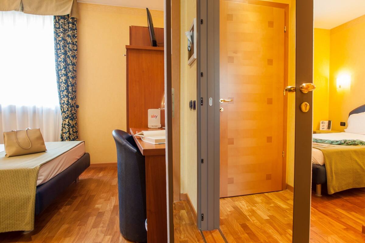 A hotel room with a bed, desk, and wardrobe.
