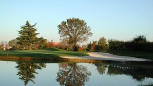 A golf course with a pond reflecting trees and a clear sky. - Corte degli Estensi (Formigine)