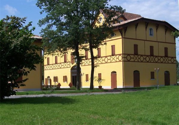 A yellow building with a symmetrical facade, multiple windows, and a central entrance.