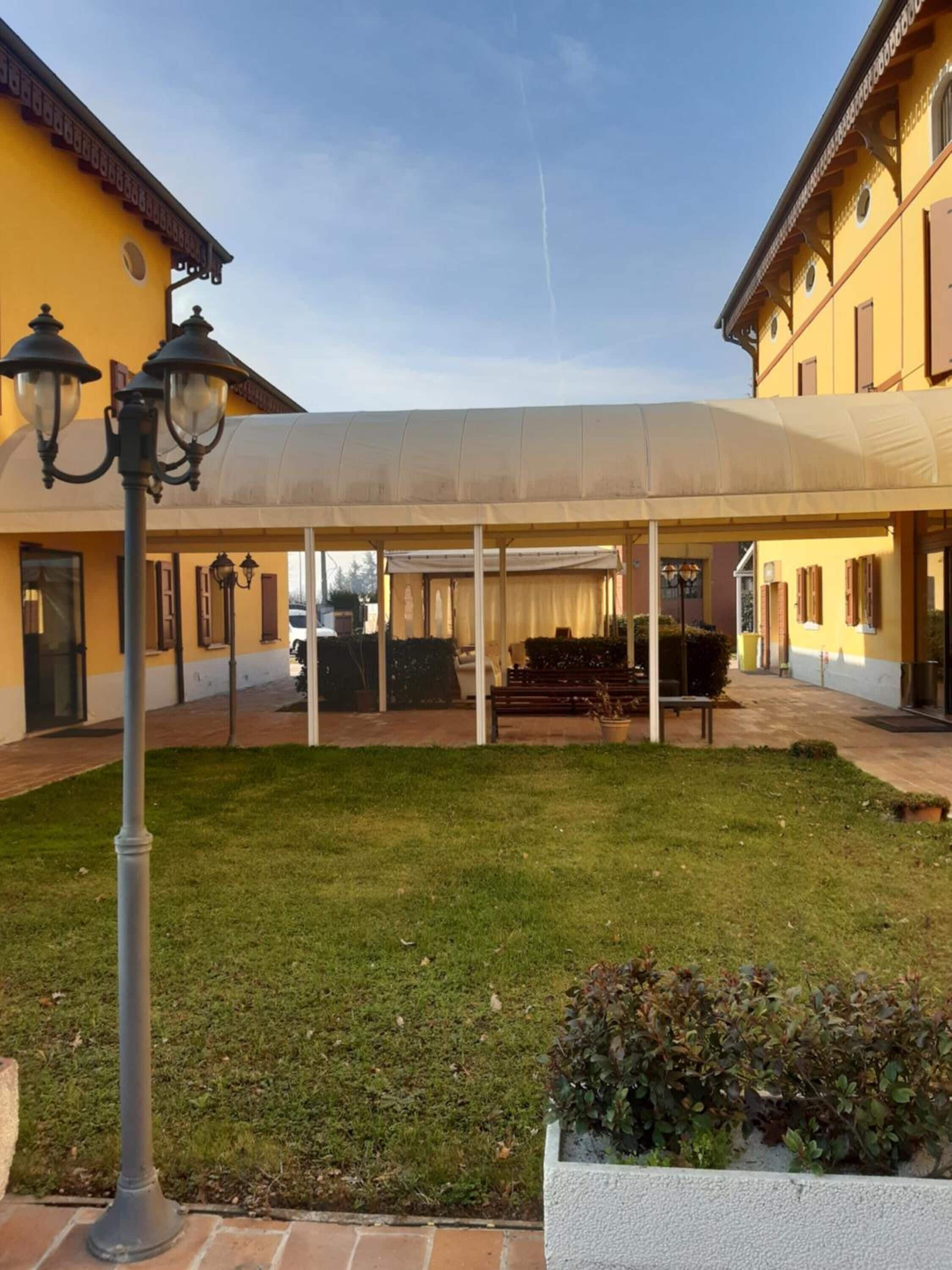 A courtyard with a covered seating area, a lamp post, and a planter with shrubs.