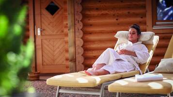 Guests can relax on a sun lounger in front of a cabin with a chevron-patterned door.
