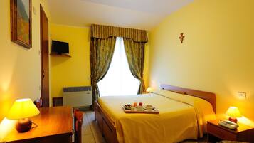 A hotel room with a bed, bedside table, lamp, and a tray with breakfast items.