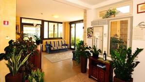 Un hall d’hôtel avec un canapé, des plantes en pot et un comptoir d’accueil.