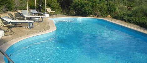 Una piscina al aire libre de temporada, sombrillas