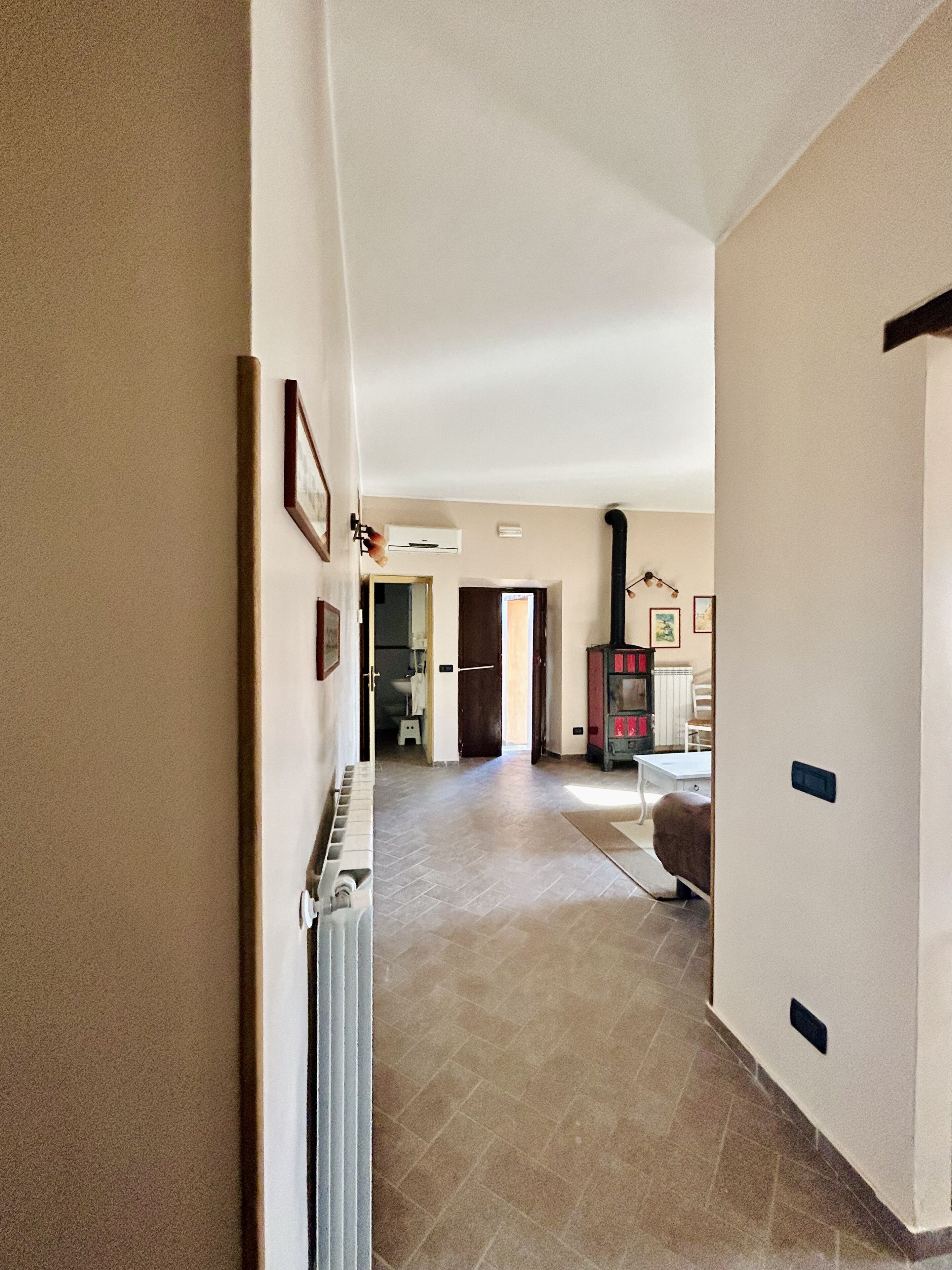 A hallway with a radiator, a fireplace, and a door leading to a bathroom.