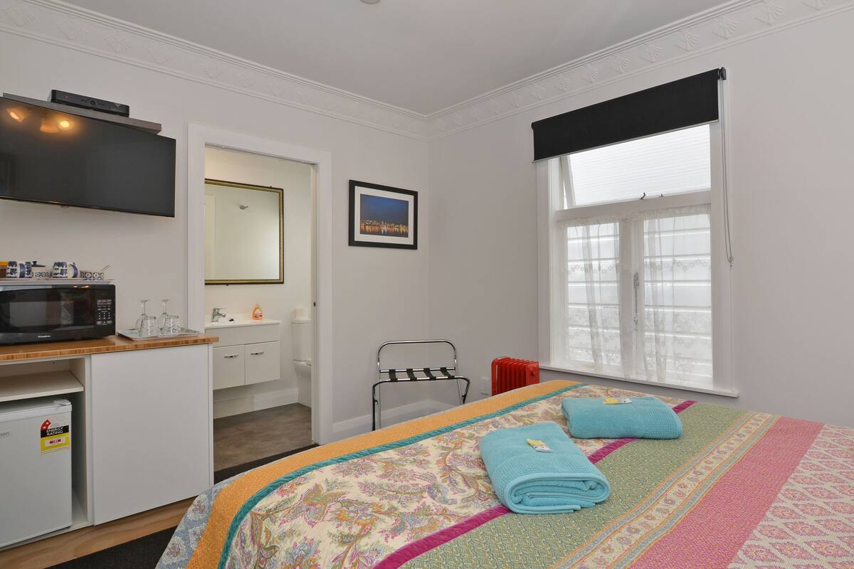 Une chambre d’hôtel comprenant un lit, un bureau avec un four à micro-ondes, un petit réfrigérateur, un lavabo, un miroir, une fenêtre avec vue et un téléviseur fixé au mur.