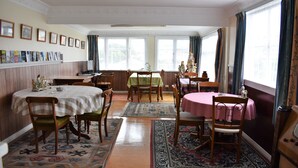 Een eetruimte met meerdere tafels, stoelen en een verzameling aan wanddecoratie.