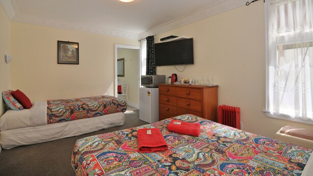 Een slaapkamer met twee bedden, een kaptafel, een televisie en een radiator.