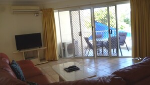 A living room with a TV, a glass coffee table, and a red sofa. - Le Lavandou Holiday Apartments (Broadbeach)