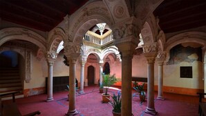An interior courtyard with arches, columns, and potted plants. - Hotel El Molino (Osuna)