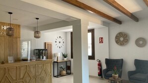A hotel lobby with a reception desk, seating area, and decorative wall clocks. - Hotel El Molino (Osuna)
