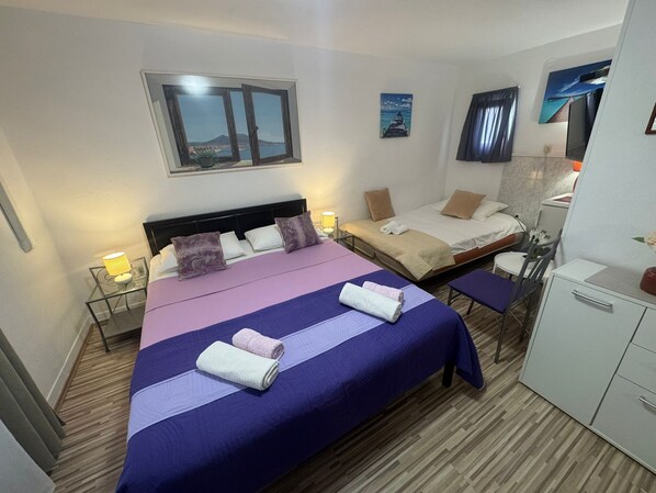 A hotel room with two beds, a desk, and a chair. There is a window with a view of a landscape.