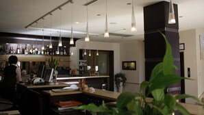 Una cocina moderna con iluminación colgante, una barra y una campana extractora negra grande.