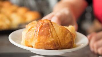 A croissant on a plate with a cup of coffee in the foreground.