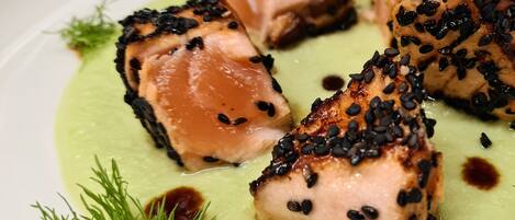 A plate of food with salmon pieces topped with black sesame seeds and garnished with dill.